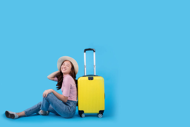 Красивые азиатские туристы садятся с багажом. Она в восторге от нового путешествия на голубом фоне
. - Фото, изображение