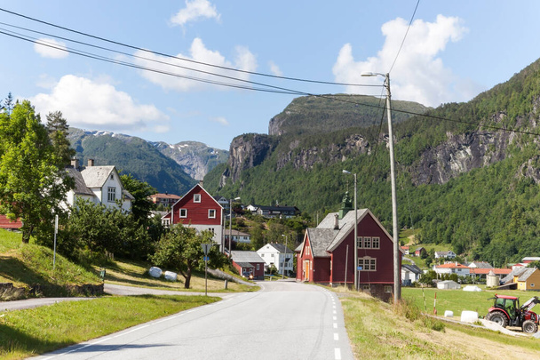 Norwegian village in mountains Road in Norway on sunny day along the fjord - Foto, imagen