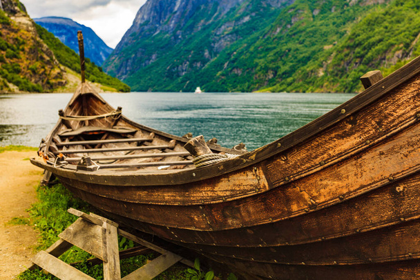 Old wooden viking boat on fjord shore. Mountains and Sognefjord. Tourism and traveling concept - Foto, imagen