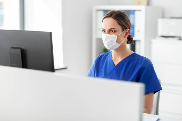 doctor or nurse in mask with computer at hospital - Fotografie, Obrázek