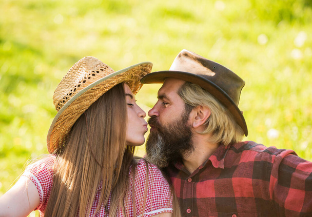 Love and harmony. Bearded cowboy in hat kissing adorable girlfriend. Couple in love. Romantic kiss. Happy couple ranch owners. Married and happy. Rustic people in love. True feelings. Enjoying life - 写真・画像
