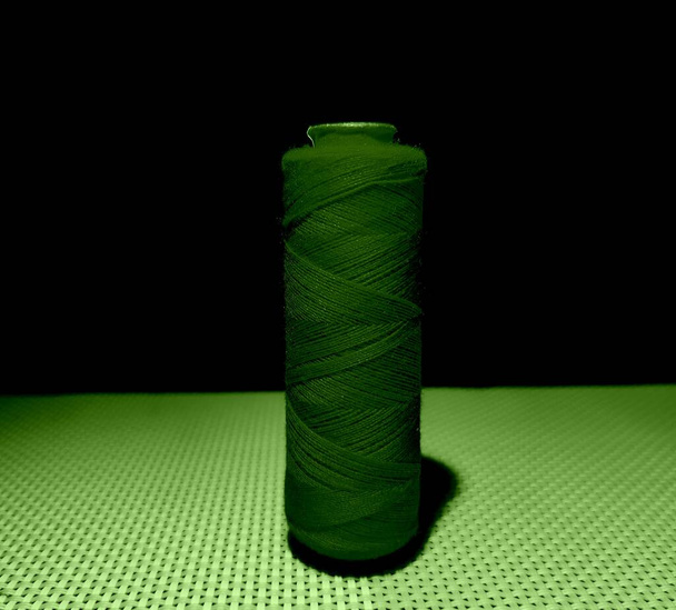 Зелений колір швейної нитки з темним фоном
. - Фото, зображення