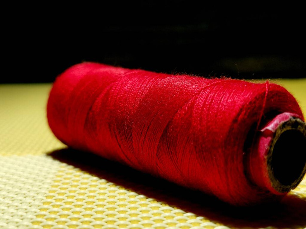 Colore rosso filo da cucire con sfondo scuro
. - Foto, immagini