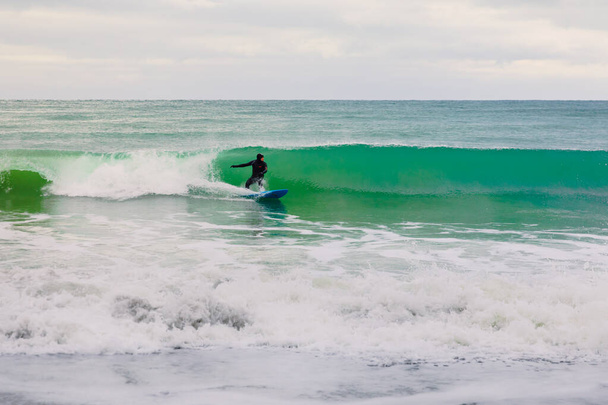 22 de novembro de 2019. Crimeia, Ucrânia. Surfista em passeio de roupa de mergulho na prancha de surf na onda do mar. - Foto, Imagem