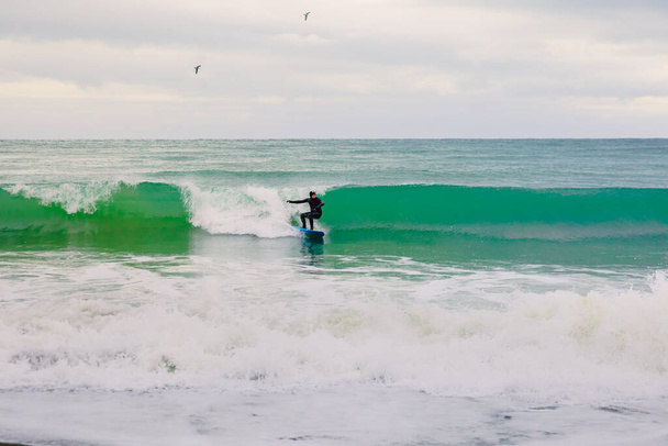 22 de noviembre de 2019. Crimea, Ucrania. Surfista en traje de neopreno paseo en tabla de surf en ola de mar. - Foto, imagen