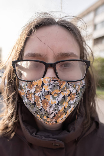 Een vrouw met een mistige bril omdat ze een medisch masker draagt tijdens een pandemie. Overlast door condensatie van de lenzen. - Foto, afbeelding