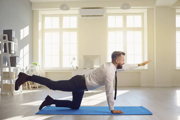 Businessman doing yoga exercises while lying in the office. - Valokuva, kuva