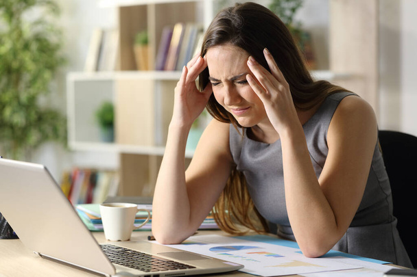 Entrepreneur woman suffering migraine attack sitting on a desk at homeoffice - 写真・画像