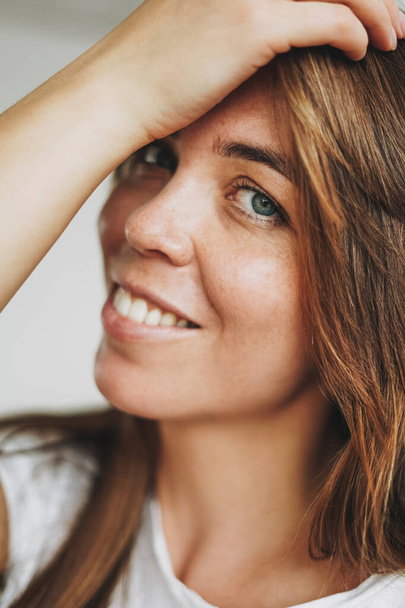 Ritratto ravvicinato di giovane donna sorridente capelli castani e occhi verdi con lentiggini in t-shirt bianca guardando la fotocamera
 - Foto, immagini
