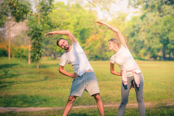 Portrait de jeune couple exercice pour la santé dans le parc au coucher du soleil. Concept sport et amour. Ton chaud
. - Photo, image