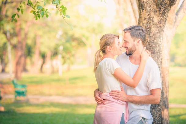 Portret młodej pary cieszącej się w parku o zachodzie słońca. Koncepcja romantyczna i miłość. Ciepły ton. - Zdjęcie, obraz