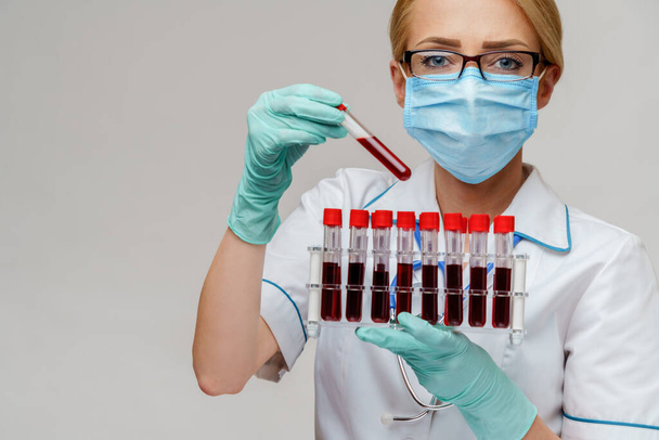medical doctor nurse woman wearing protective mask and gloves - holding rack with virus blood tests - Foto, Bild