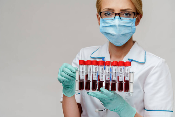 medical doctor nurse woman wearing protective mask and gloves - holding rack with virus blood tests - Foto, Bild