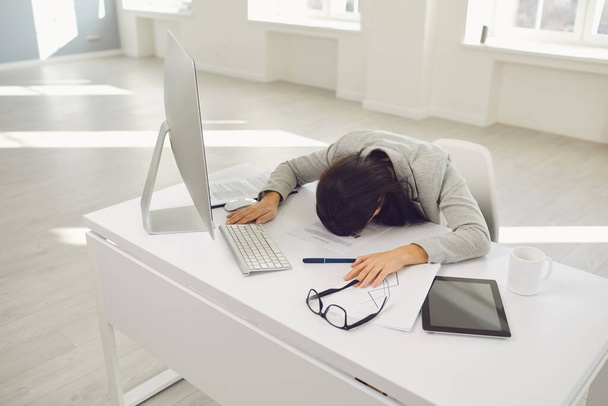 Tired business woman lies asleep at the desk workplace in the office. - Foto, Bild