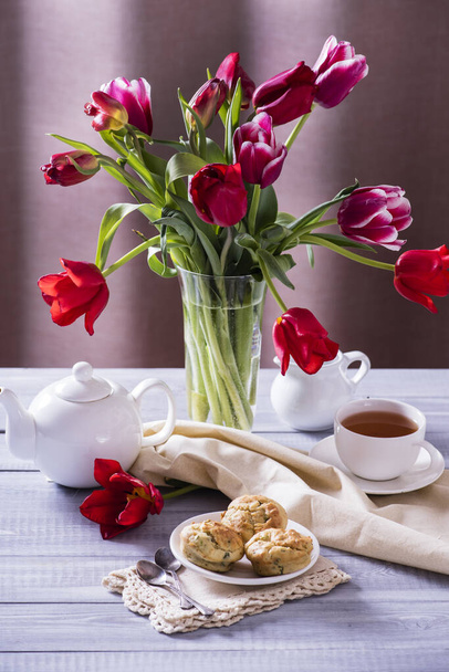 Tasty apple muffins with a beautiful bouquet of red tulips on a wooden background. - Foto, Imagem