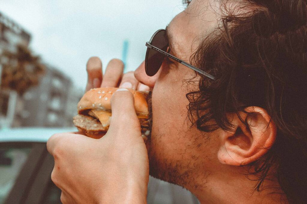 Il ragazzo morde un hamburger con un appetito
 - Foto, immagini