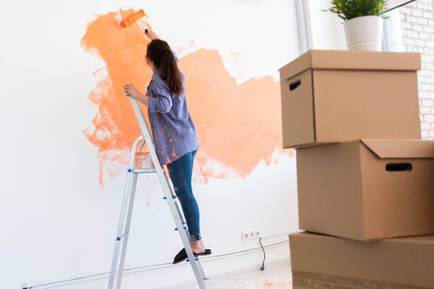 Beautiful woman painting wall in her new apartment. Renovation and redecoration concept. - Fotoğraf, Görsel