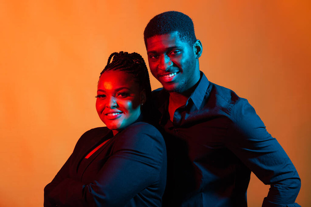 Dark neon portrait of young african american man and woman. Red and blue light. - Foto, Bild