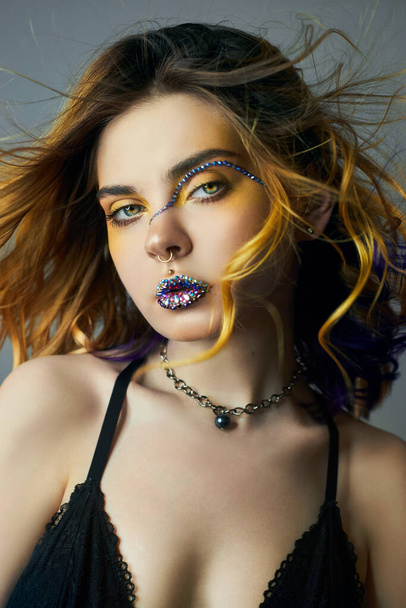 Woman with creative yellow coloring hair and makeup with rhinestones, purple strands of hair second layer. Bright color curly hair on the girl's head, professional makeup - Фото, изображение