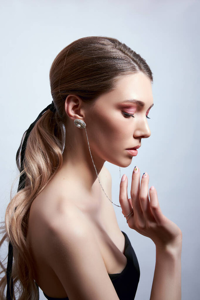 Beauty portrait of a woman with long hair, earrings in her ears and expensive jewelry on her hands - Foto, Imagem