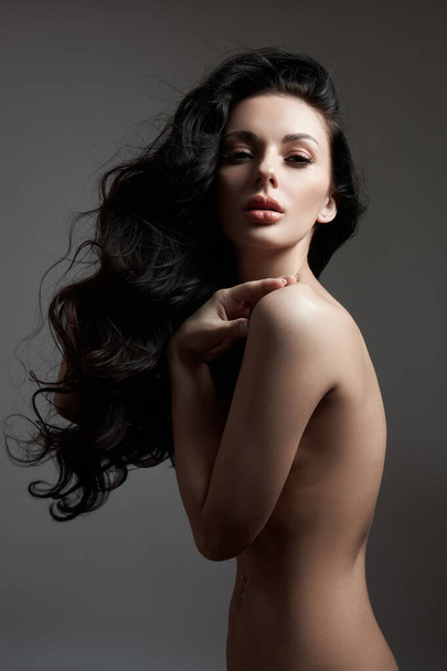 Sexy fashion nude woman with long hair, curly strong hair of a brunette girl. Natural cosmetics for hair care, strong roots - Fotó, kép