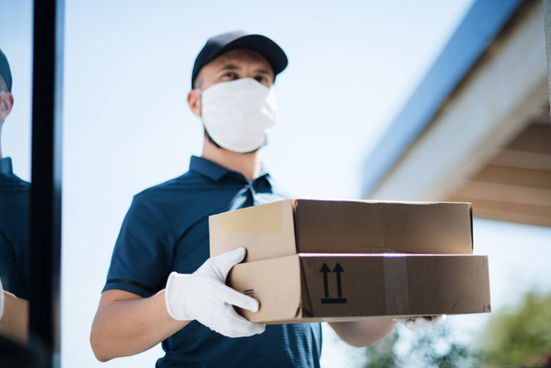 Courier with face mask delivering parcel, corona virus and quarantine concept. - Fotoğraf, Görsel