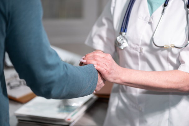 Female doctor holding patient hand for encouragement - Photo, Image