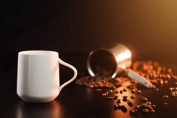 Біла красива чашка чаю або свіжозварена кава стоїть на красивому темно-золотому фоні. Прекрасно обсмажені кавові зерна
 - Фото, зображення