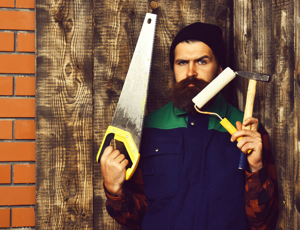 bearded painter holding various building tools with serious face - 写真・画像