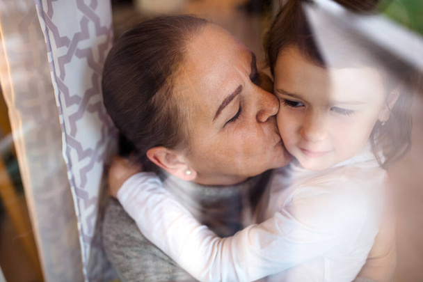 Senior grandmother kissing small granddaughter indoors at home. - Fotó, kép