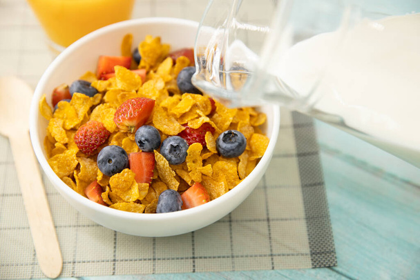 Terveellinen aamiainen. Kaada maitoa kannusta murokulhoon ja hedelmiä puupöydälle. Terveellinen ruoka
 - Valokuva, kuva