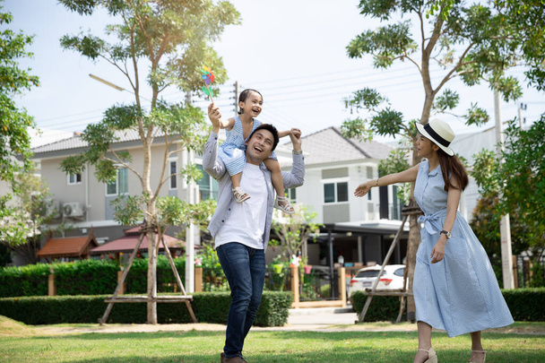 Gelukkige Aziatische familie. Vader gaf zijn dochter een meelift in een park bij natuurlijk zonlicht achtergrond en huis. Familie vakantie concept met kopieerruimte - Foto, afbeelding