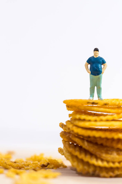 Miniature people, Fat man standing on potato chips on white background (food concept) - Photo, Image