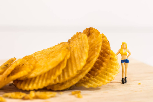 Miniature people, Female model stand beside potato chips to present products.(food concept) - Photo, Image