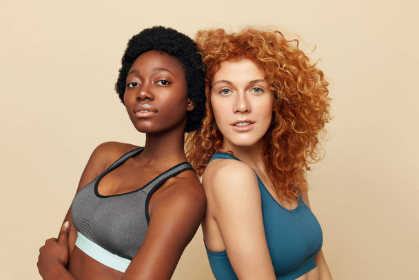 Fitness Women. Ethnic Sporty Girls Close Up Portrait. Beautiful Brunette And Redhead Posing On Beige Background. Sport For Active Lifestyle.  - Foto, afbeelding