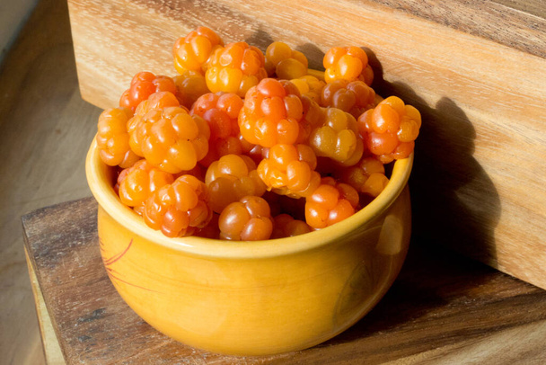 Cloudberry Rubus chamaemorus close up in orange bowl on wooden table,harvest in norwegian mountains near Hemsedal ski resort,Buskerud,Norway,photo for printing on calendar,poster,wallpaper - Photo, Image