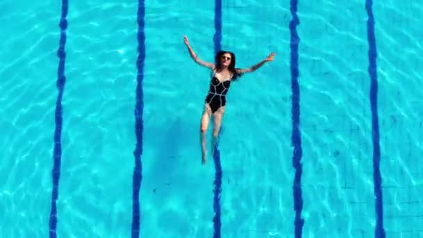 Beautiful girl swims in the pool and enjoys the scenery - Záběry, video