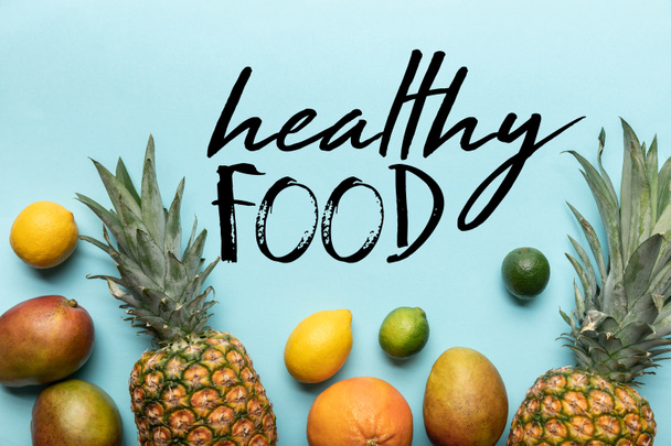 верхний вид цельных спелых тропических фруктов на голубом фоне с иллюстрацией здоровой пищи
  - Фото, изображение