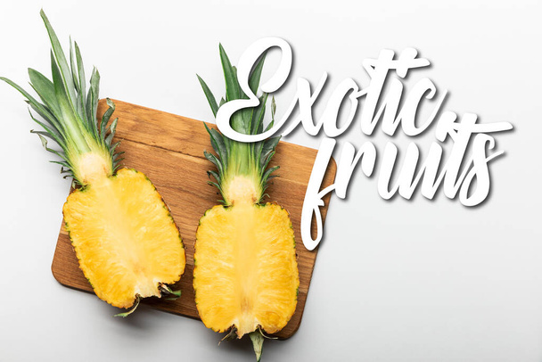 vue du dessus de l'ananas jaune mûr coupé sur planche à découper en bois sur fond blanc avec illustration de fruits exotiques
 - Photo, image