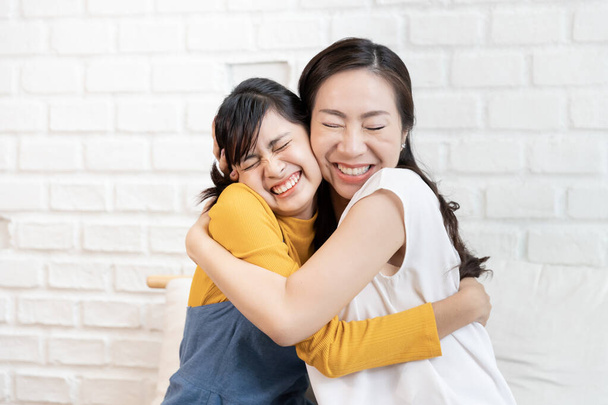 Happy Asian family Mom and teenage daughter embrace together excited, glad in a room that has sunlight from the window at home. Show Love family concept - Photo, Image