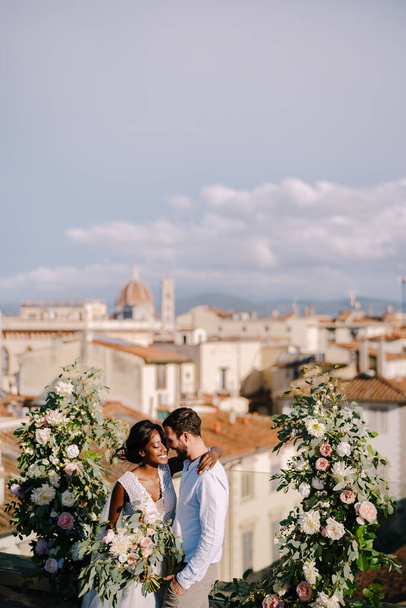 Matrimonio interrazziale. Destinazione matrimonio d'arte a Firenze, Italia. Una cerimonia nuziale sul tetto dell'edificio, con vista sulla città e sulla Cattedrale di Santa Maria Del Fiore
 - Foto, immagini