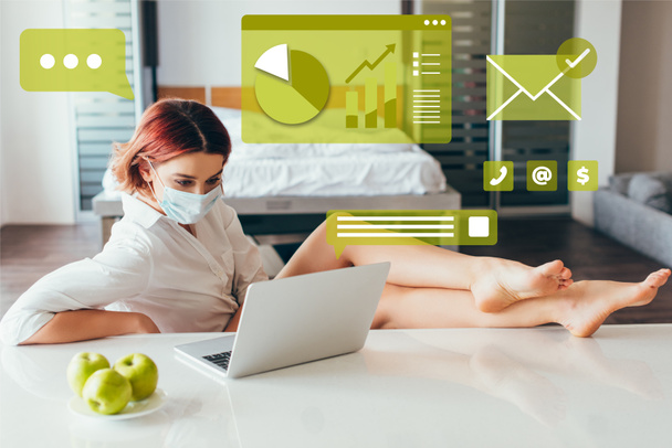 Barfuß-Freelancer in medizinischer Maske arbeitet zu Hause am Laptop mit Äpfeln auf Selbstisolation mit Business-Grafiken - Foto, Bild