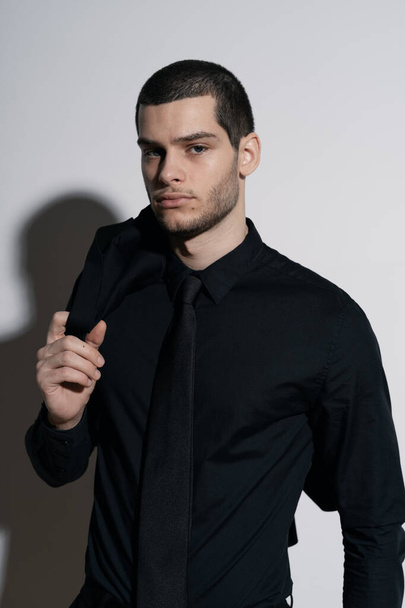 Young handsome businessman in black shirt and black suit - 写真・画像