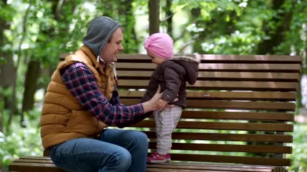 Un padre y su hija están jugando en un banco del parque.
. - Metraje, vídeo