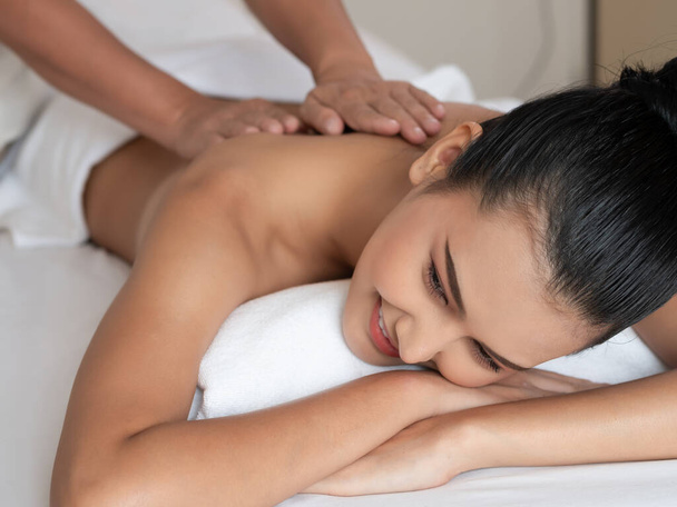 Aziatische vrouw ontspannen en glimlachen op bed matrassen in de Spa. Thaise massage voor de gezondheid. - Foto, afbeelding