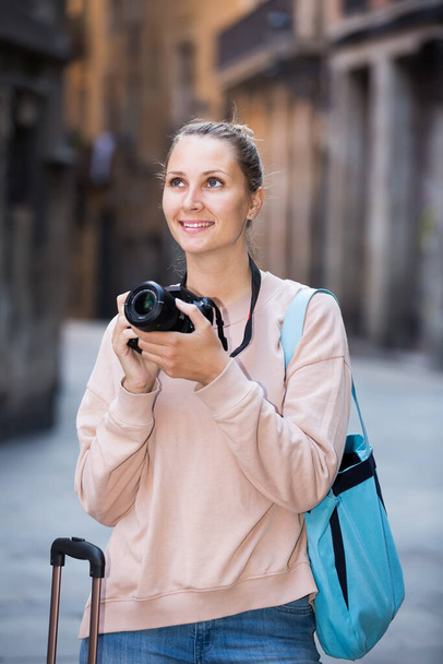  smiling tourist girl with a camera walks around the city - Zdjęcie, obraz