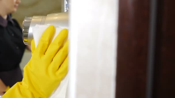 Υπηρεσία καθαρισμού, close-up Housemaid από το προσωπικό του ξενοδοχείου με στολή και προστατευτικά γάντια καθαρισμού μπάνιο ξενοδοχείο στεγνωτήρα μαλλιών με σκουπίστε. απολύμανση επιφανειών από ρύπους, βακτήρια ή ιούς. 4 k βίντεο - Πλάνα, βίντεο