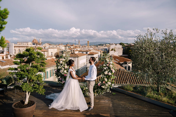 Cílová výtvarná svatba ve Florencii, Itálie. Multietnický svatební pár. Svatební obřad na střeše budovy s výhledem na město a katedrálu Santa Maria Del Fiore - Fotografie, Obrázek