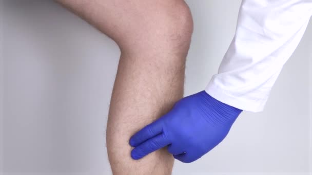 A man suffers from pain in the calves. Stretching the calf muscle, varicose veins, leg cramps, or myositis. Orthopedic doctor examines - Footage, Video