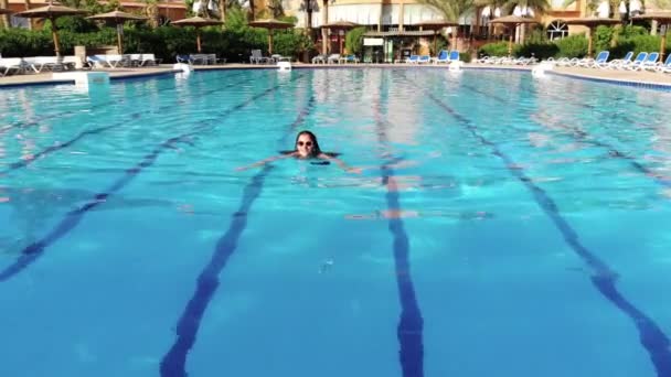 Beautiful women swims in the pool and enjoys the scenery - Záběry, video